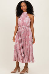 woman wearing a pink floral pleated halter dress with a tie waist and knee-length skirt