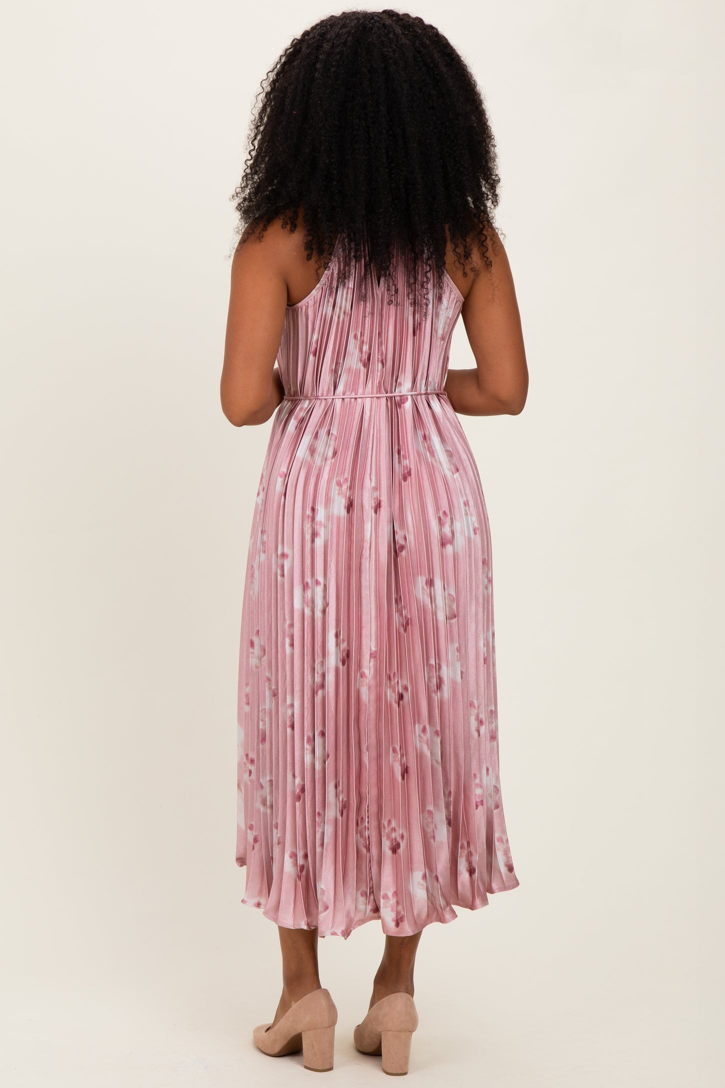woman wearing a pink pleated midi dress with floral print, shown from the back