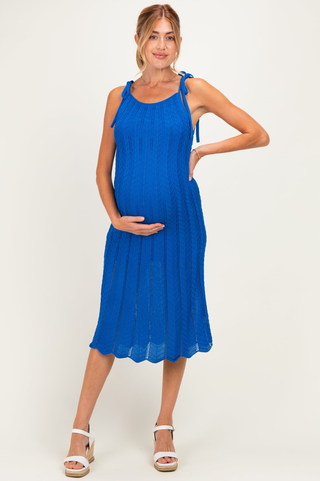 woman wearing a bright blue knitted maternity dress with tie straps and a visible baby bump