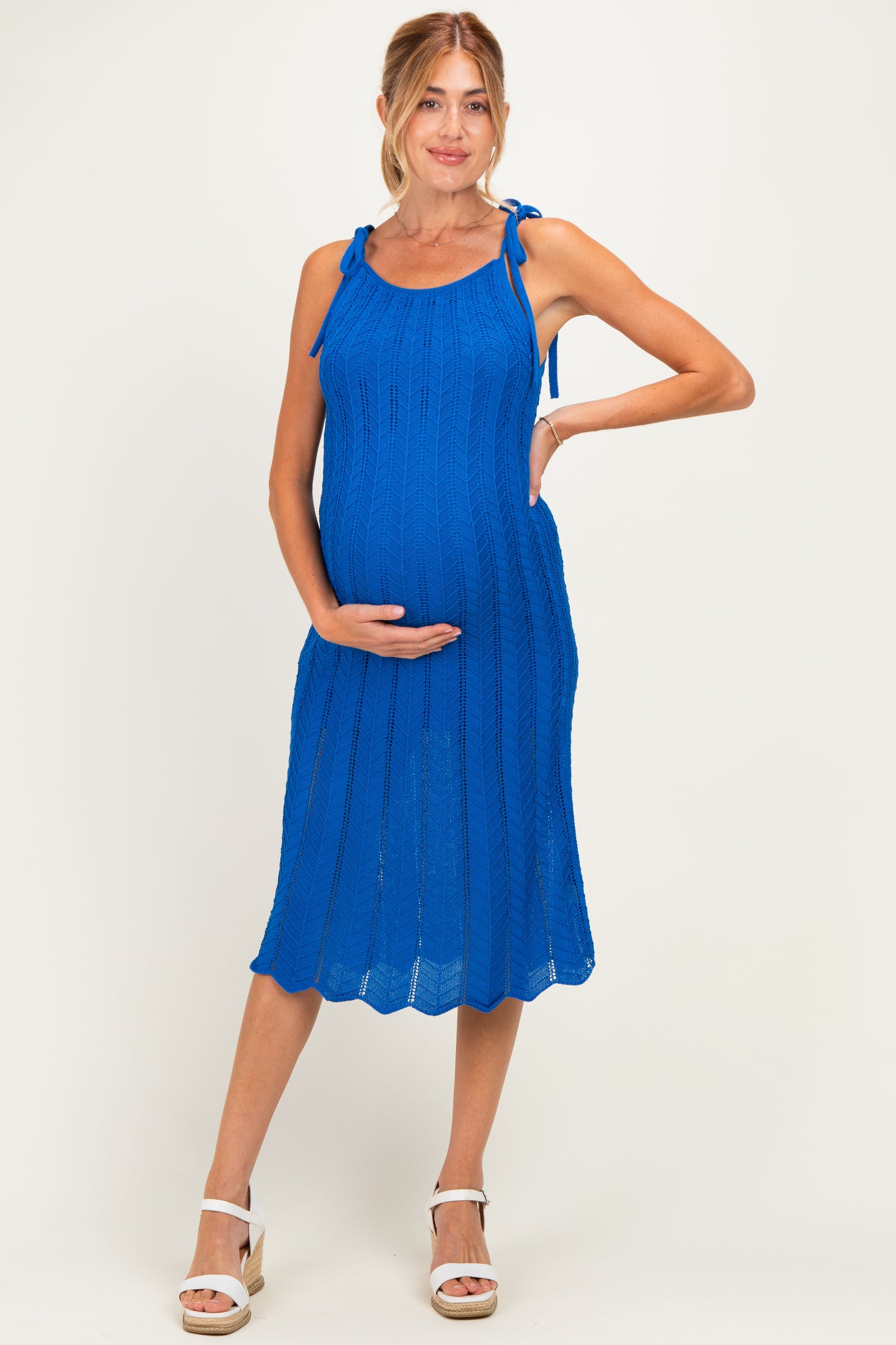woman wearing a bright blue knitted maternity dress with tie straps and a visible baby bump