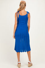 woman wearing a blue knitted maternity dress with adjustable tie straps and a mid-length hemline