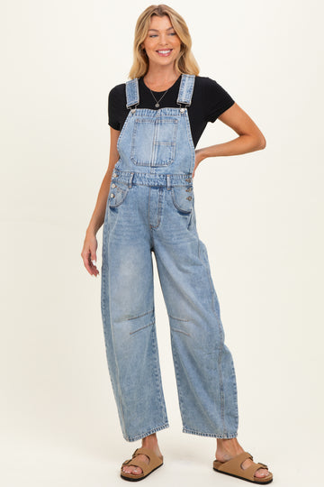 woman wearing light blue maternity overalls with wide-leg design, styled with a black t-shirt and sandals, smiling