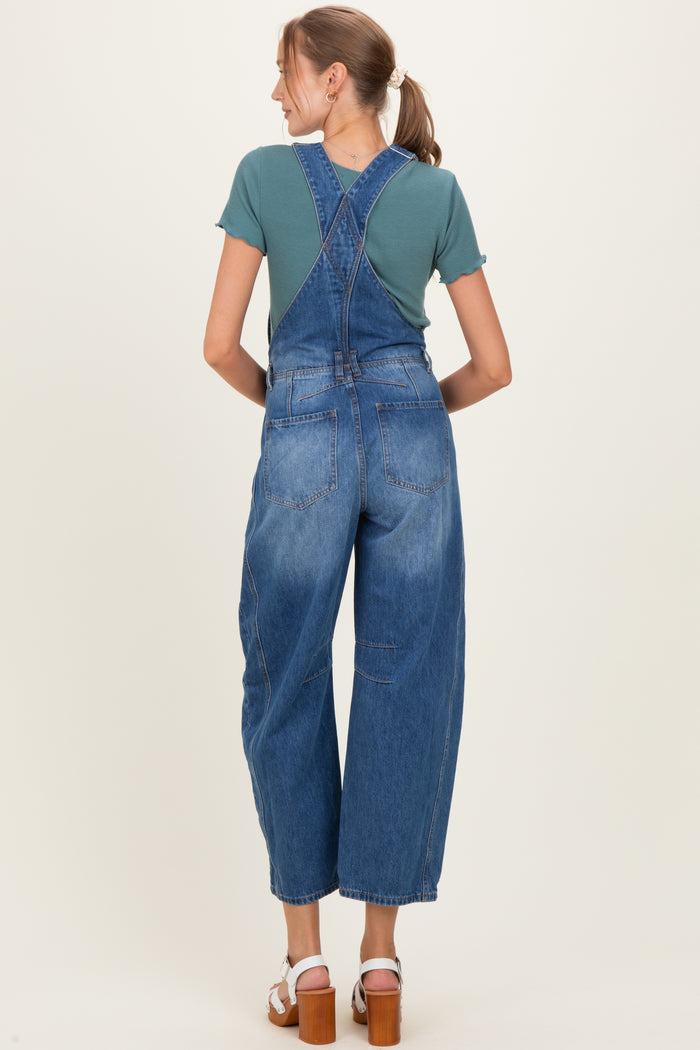 woman wearing a teal short sleeve top and blue maternity overalls, viewed from the back