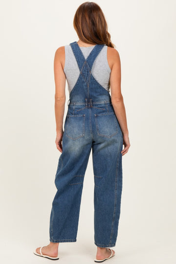 woman wearing a gray tank top and blue denim overalls viewed from the back