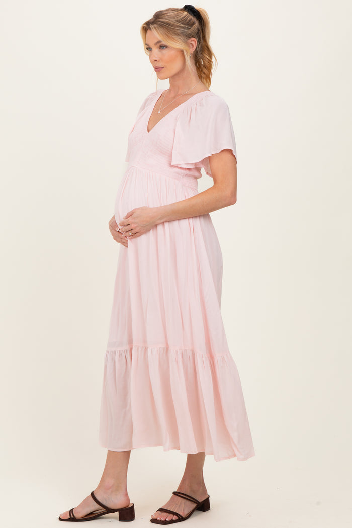 woman wearing a pink maternity maxi dress with flutter sleeves and a baby bump