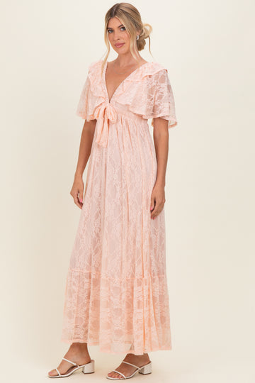 woman wearing a light pink lace maxi dress with flutter sleeves and a tie front detail