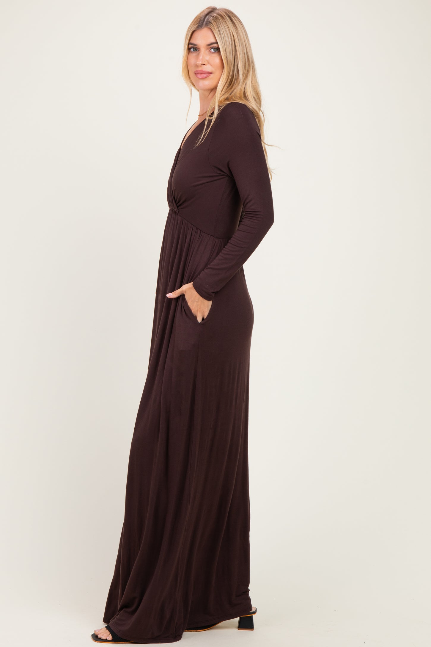 woman wearing a chocolate brown long sleeve maxi dress with a cinched waist and side pockets