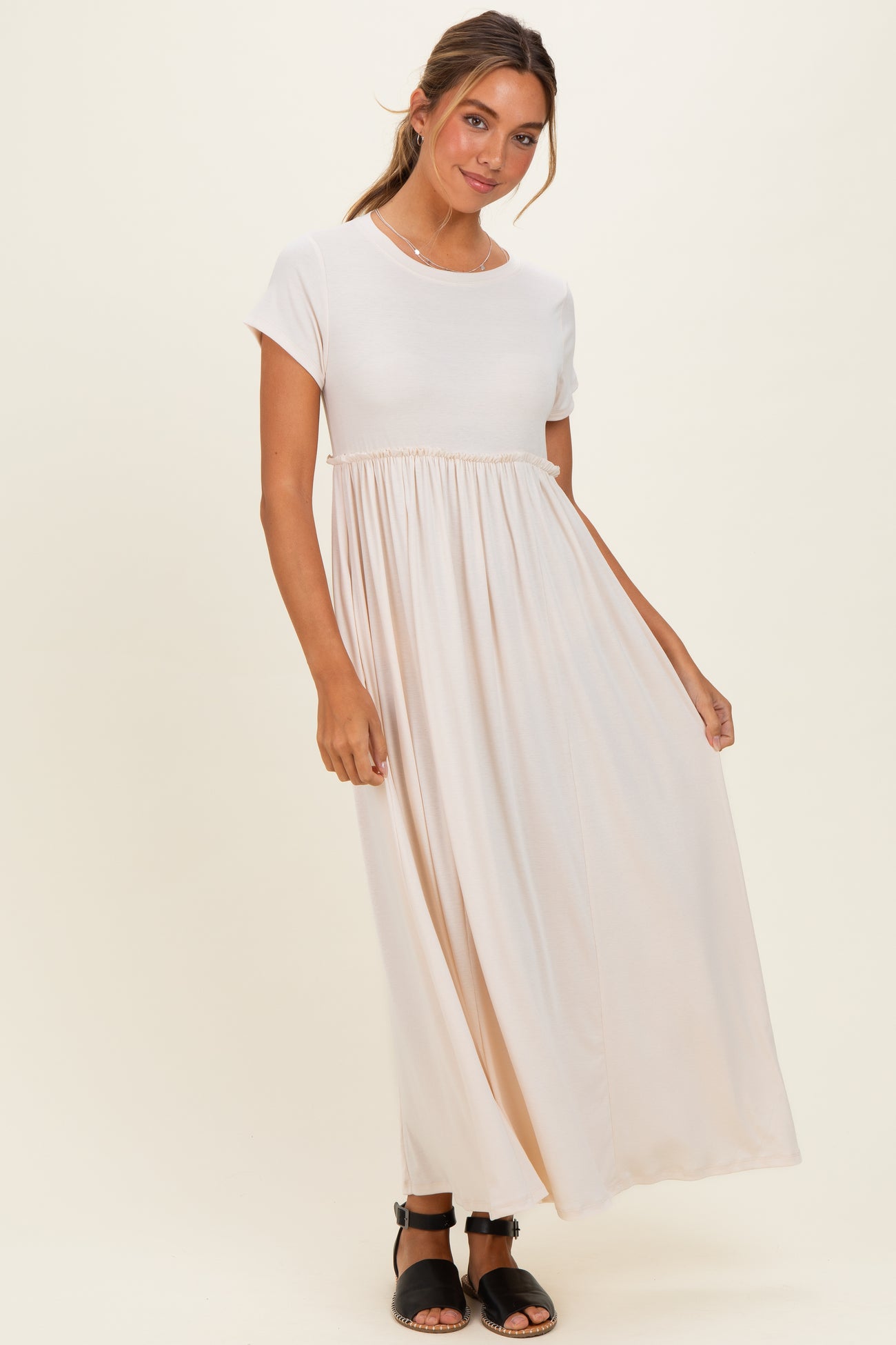 woman wearing a cream short sleeve maxi dress with an empire waist and a flowing skirt
