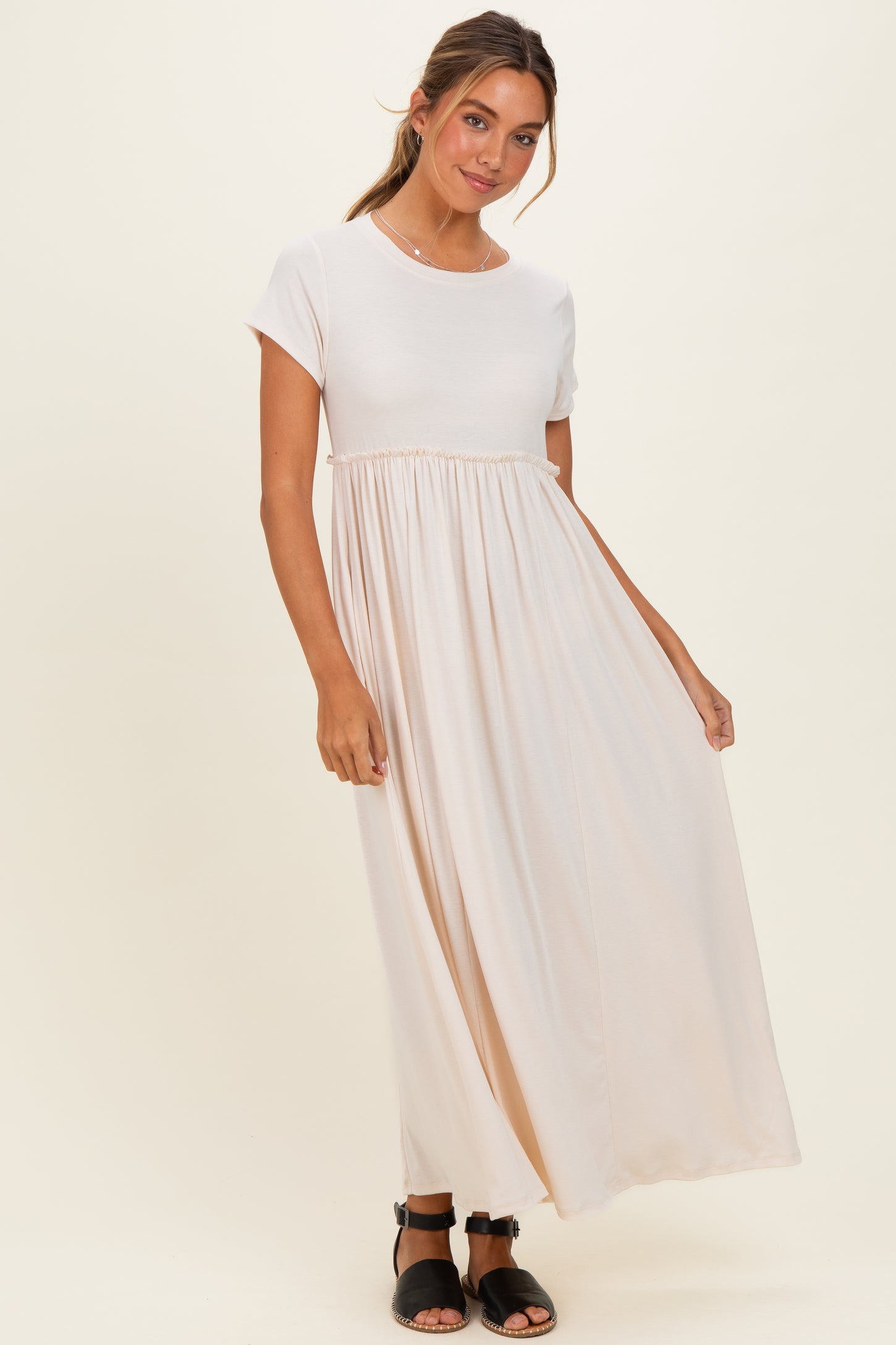 woman wearing a cream short sleeve maxi dress with an empire waist and a flowing skirt