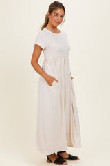 woman wearing a beige short sleeve maxi dress with a gathered waist and pockets, styled casually
