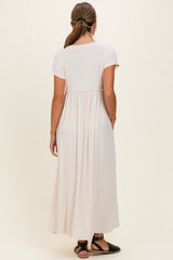 woman wearing a light pink short sleeve maxi dress with a gathered back and side pockets