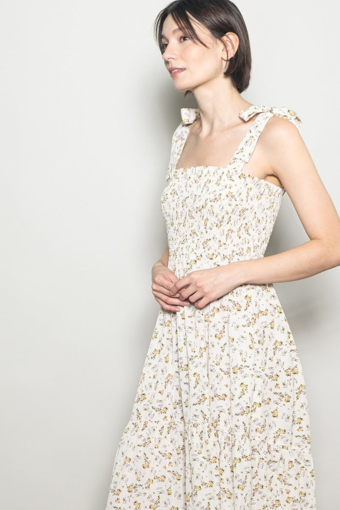 woman wearing a floral print square neck dress with tie straps and a flowy skirt