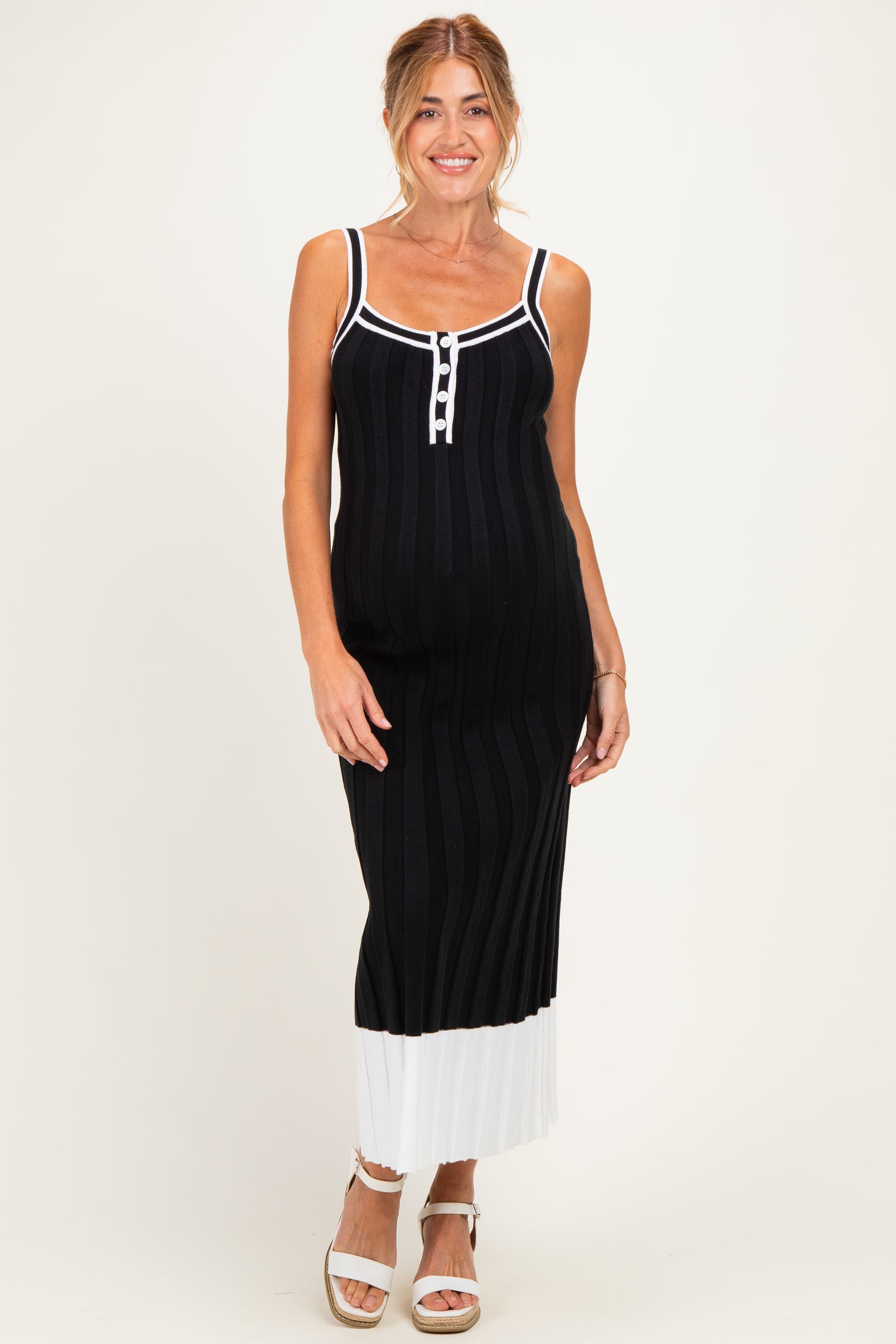 woman wearing a black and white striped maternity dress with a button detail and a fitted silhouette, showcasing her baby bump