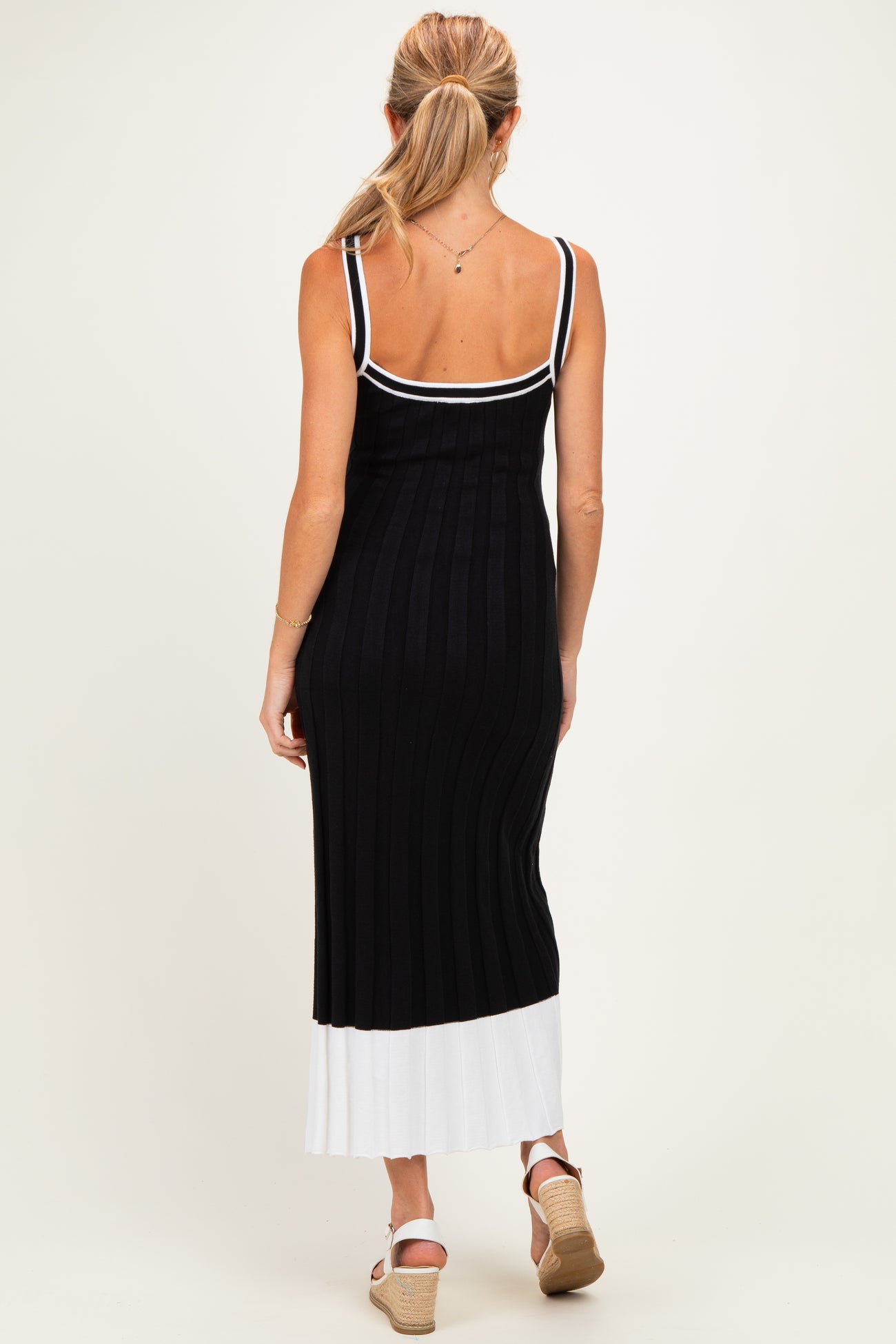 woman wearing a black and white striped maternity maxi dress with a fitted silhouette and spaghetti straps