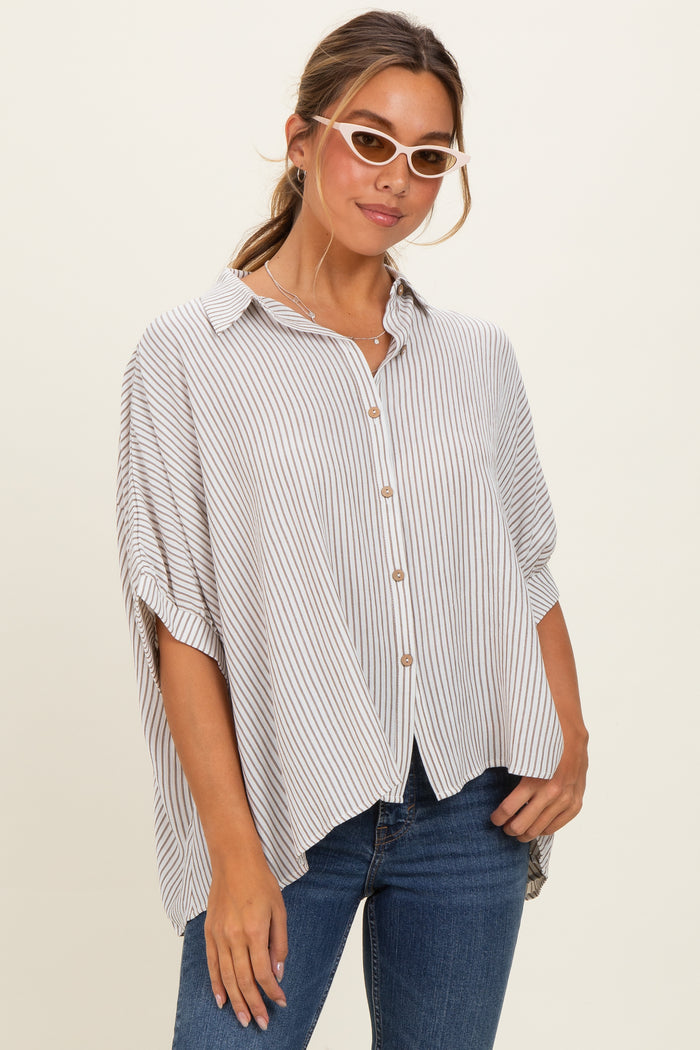 woman wearing a striped button-up shirt with rolled sleeves and a loose fit, paired with blue jeans