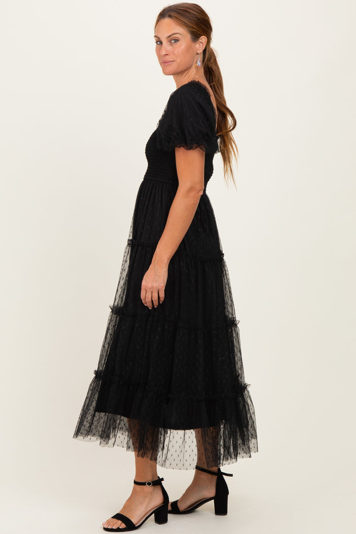 woman wearing a black tiered tulle midi dress with puff sleeves and a fitted bodice, standing in profile