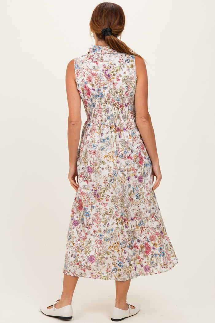 woman wearing a sleeveless floral maxi dress with a smocked back, standing with her back to the camera