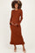 woman wearing a rust long sleeve ribbed maternity dress with ruffle hem and baby bump visible