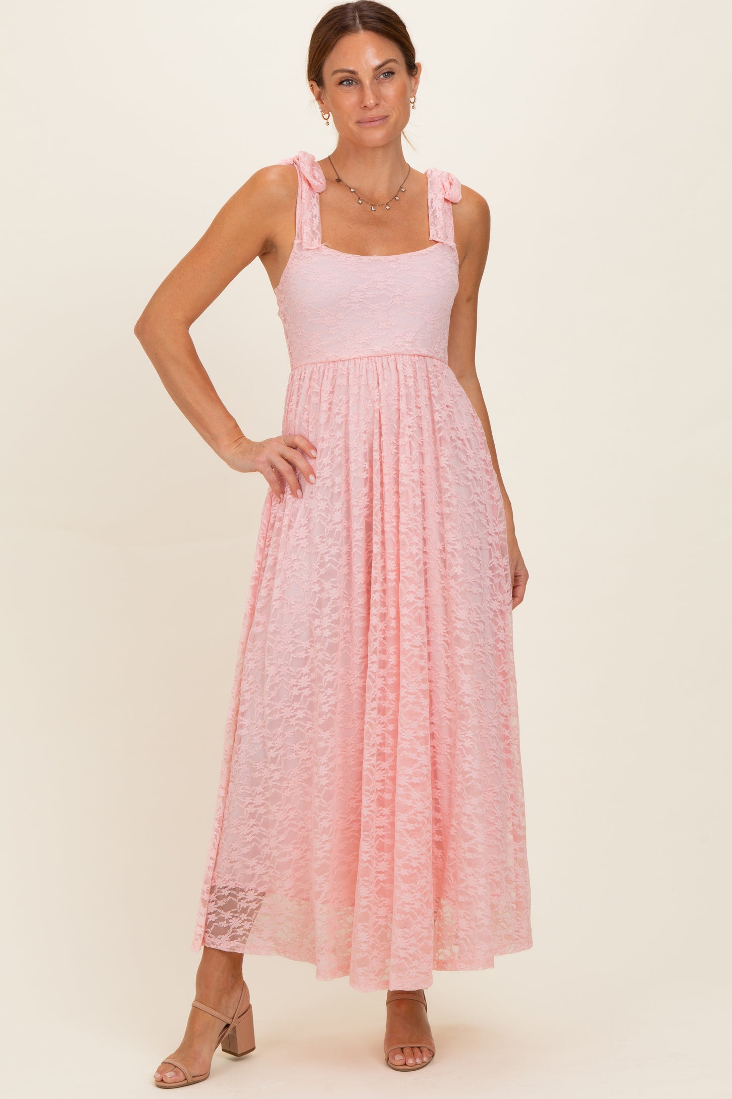 woman wearing a pink lace maxi dress with tie straps and a flowing skirt