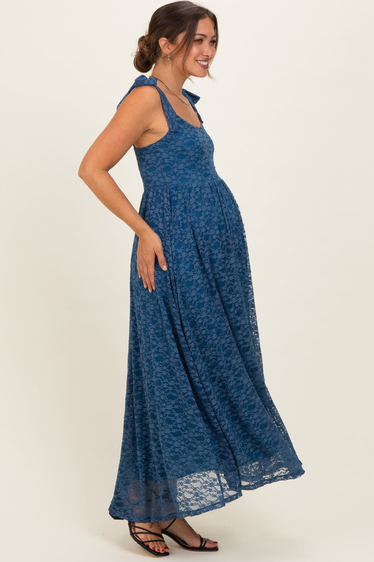 woman wearing a blue lace maxi maternity dress with a baby bump and tied straps