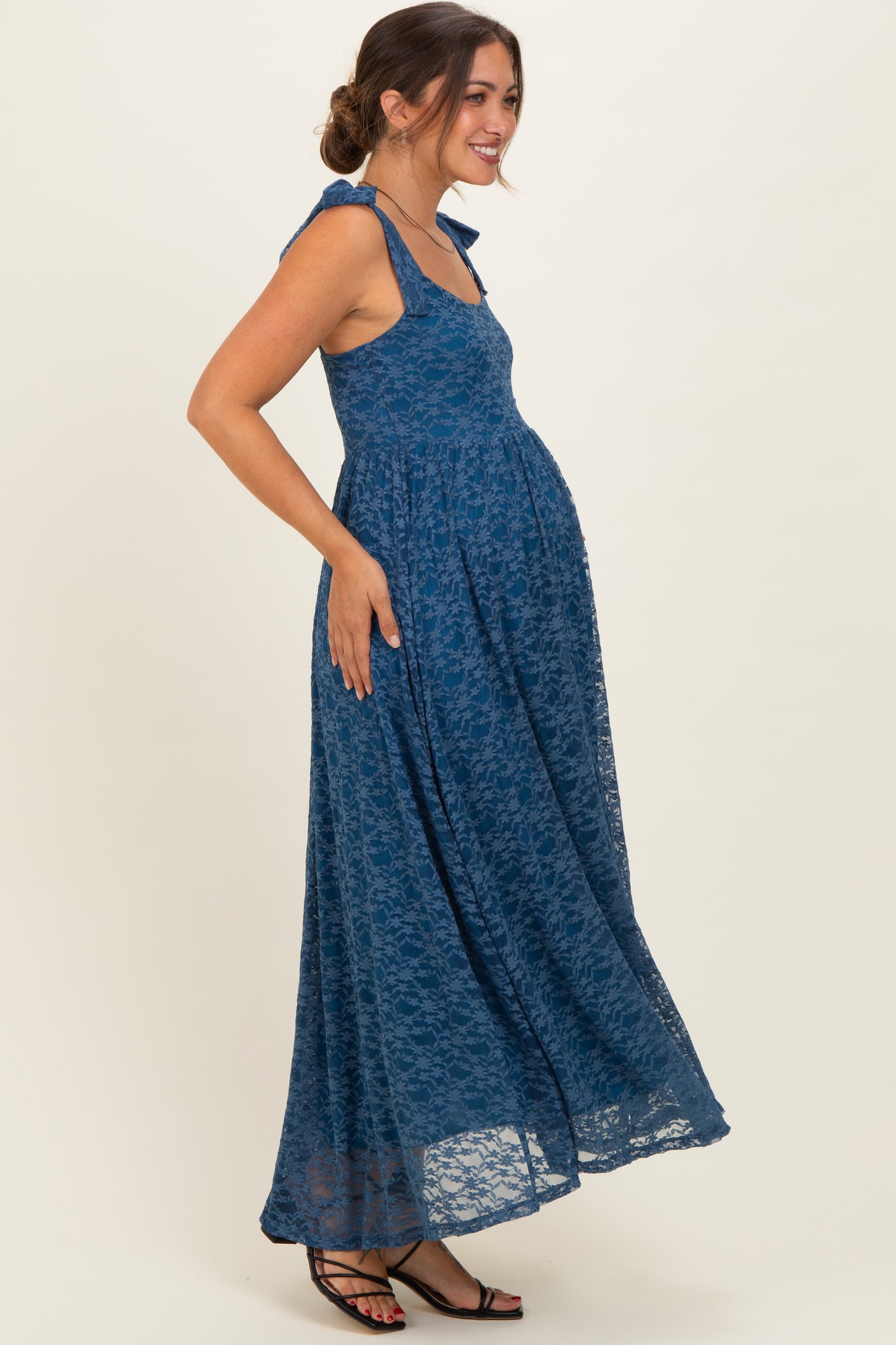 woman wearing a blue lace maxi maternity dress with a baby bump and tied straps