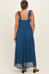 woman wearing a dark teal lace maternity maxi dress with tie shoulder straps and a flowing skirt, seen from the back