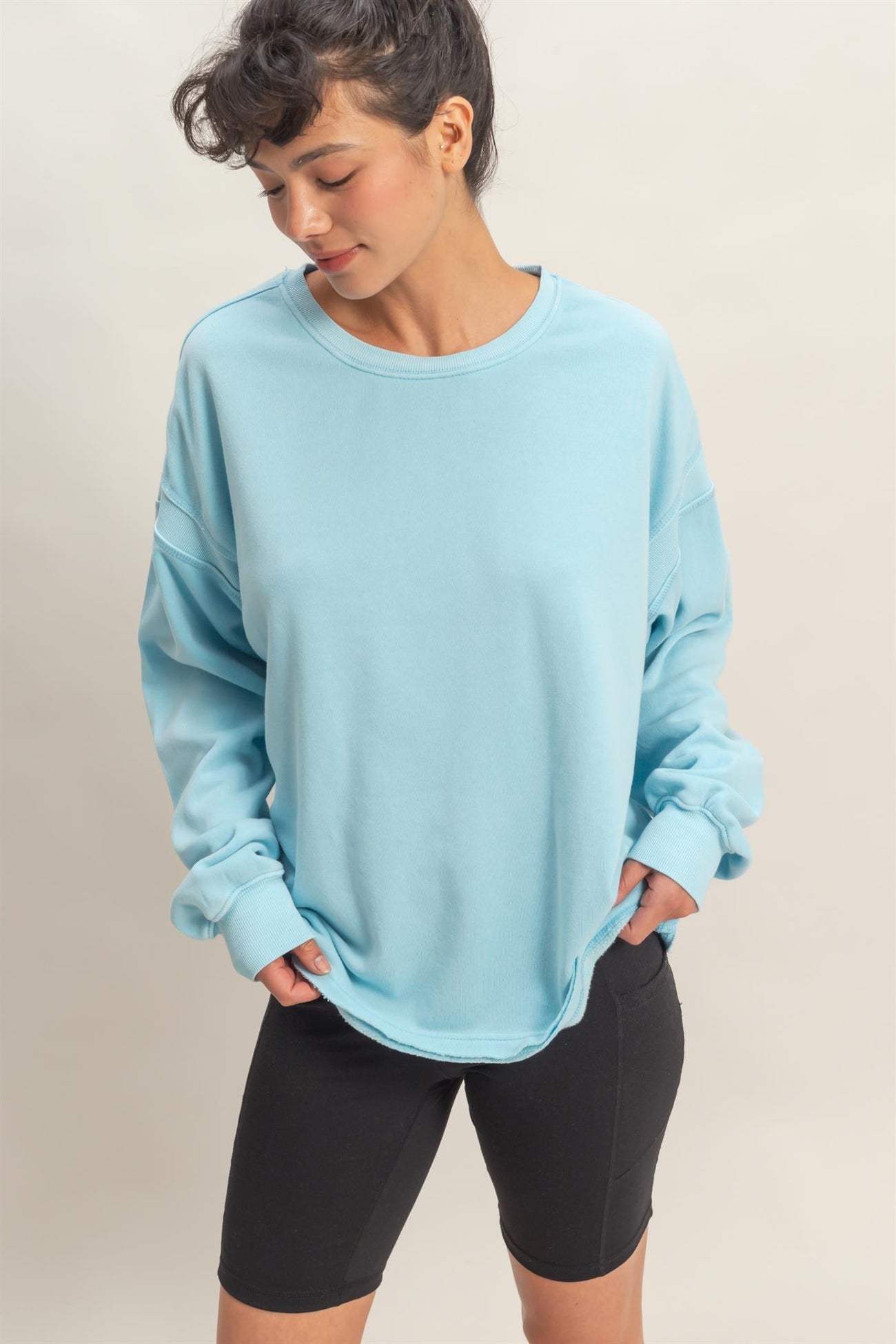 woman wearing a light blue oversized sweatshirt paired with black bike shorts