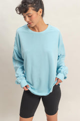 woman wearing a light blue oversized sweatshirt paired with black bike shorts