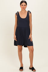 woman wearing a navy blue sleeveless romper with tie straps and a flared skirt, standing casually