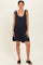 woman wearing a navy blue sleeveless romper with tie straps and a flared skirt, standing casually