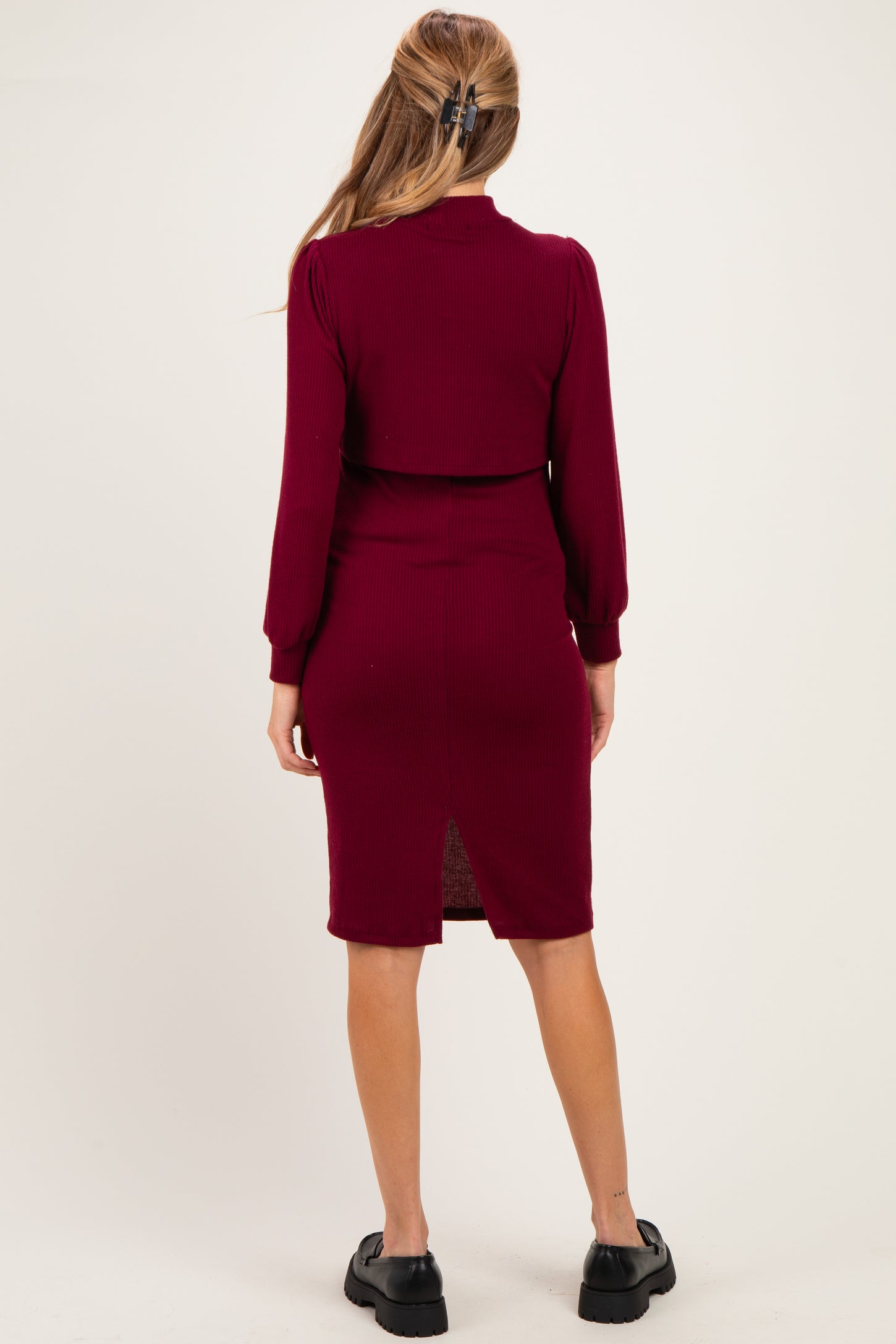 woman wearing a burgundy ribbed maternity dress with a back slit and long sleeves