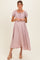 woman wearing a light pink maternity maxi dress with puff sleeves and a smocked bodice, holding her baby bump