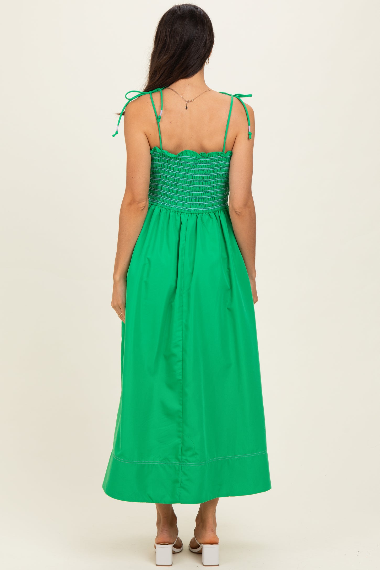 woman wearing a bright green maxi dress with adjustable tie straps and a smocked bodice visible from the back