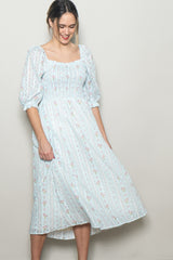 woman wearing a light blue floral midi dress with puff sleeves and a smocked bodice