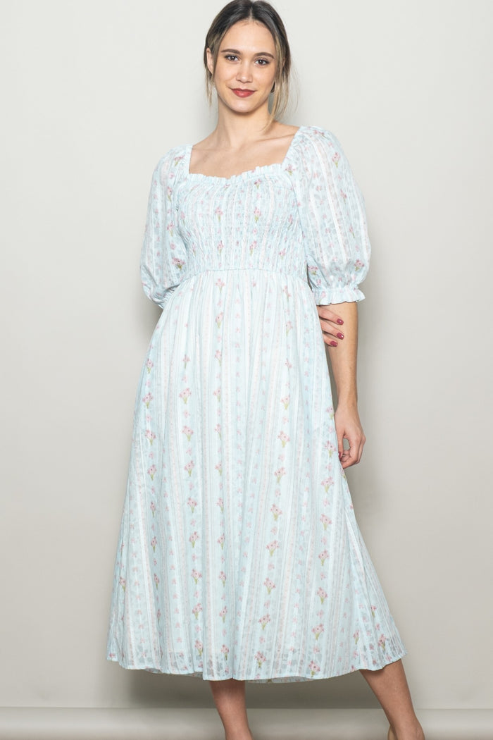 woman wearing a light blue floral midi dress with puff sleeves and a smocked bodice