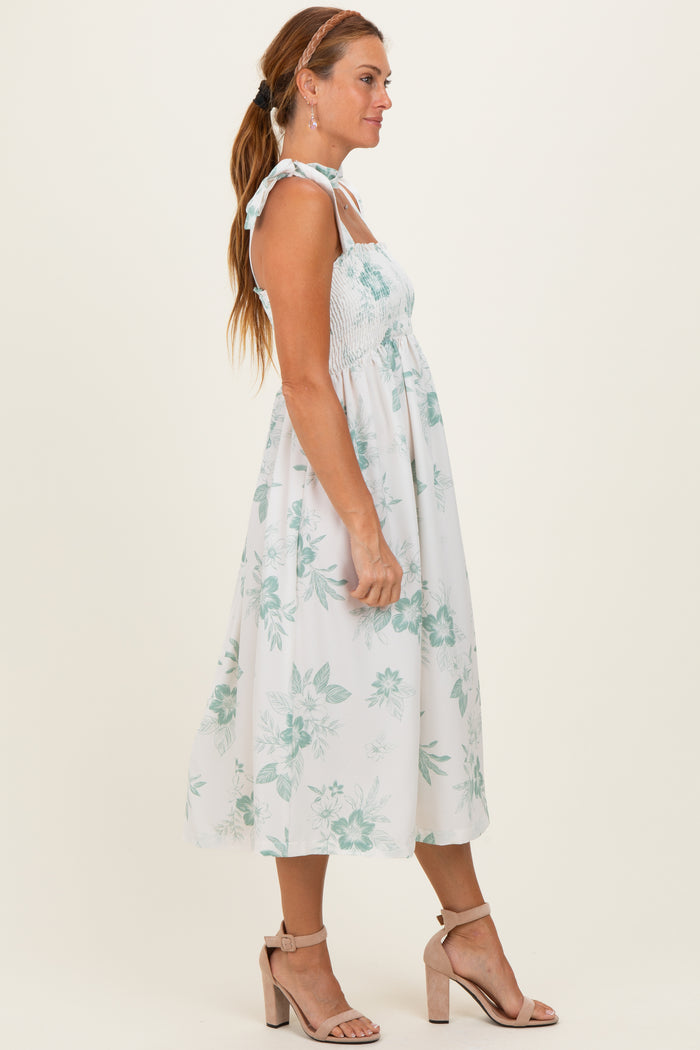 woman wearing a white floral sundress with smocked bodice and tie straps, paired with strappy nude heels