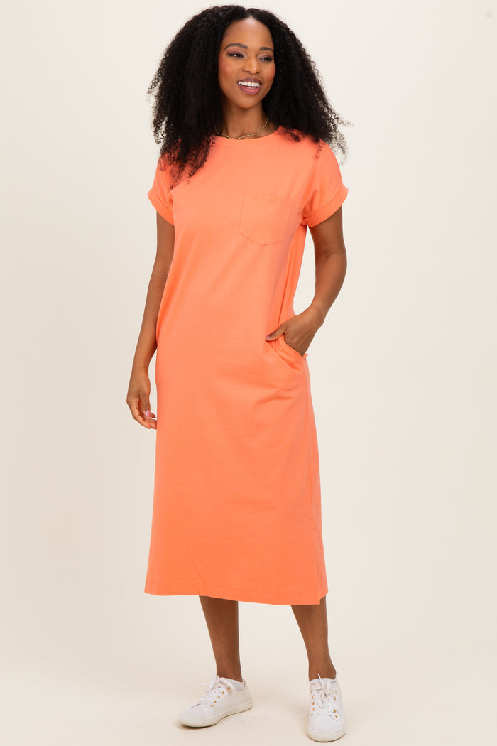 woman wearing an orange short sleeve t-shirt dress with a pocket and side pockets, standing and smiling