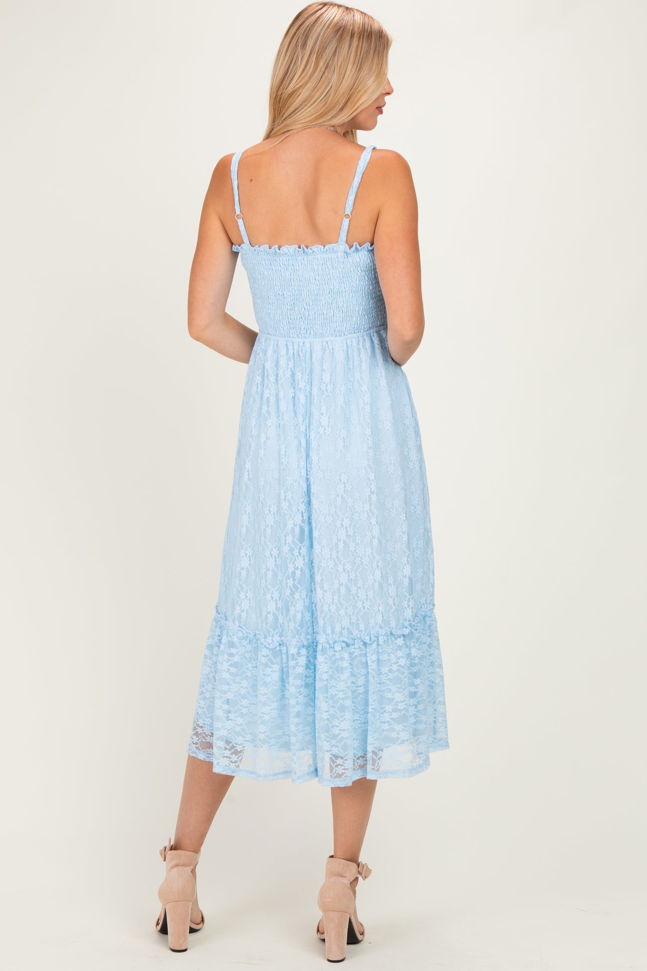 woman wearing a light blue lace midi dress with a fitted bodice and tiered ruffle hem, seen from the back
