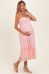 woman wearing a pink lace maternity dress and holding her baby bump