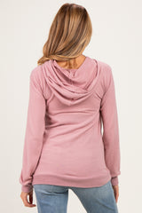 woman wearing a light pink maternity hoodie with a hood, showing the back view and casual fit