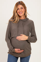 woman wearing a brown maternity hoodie and holding her baby bump with a smile