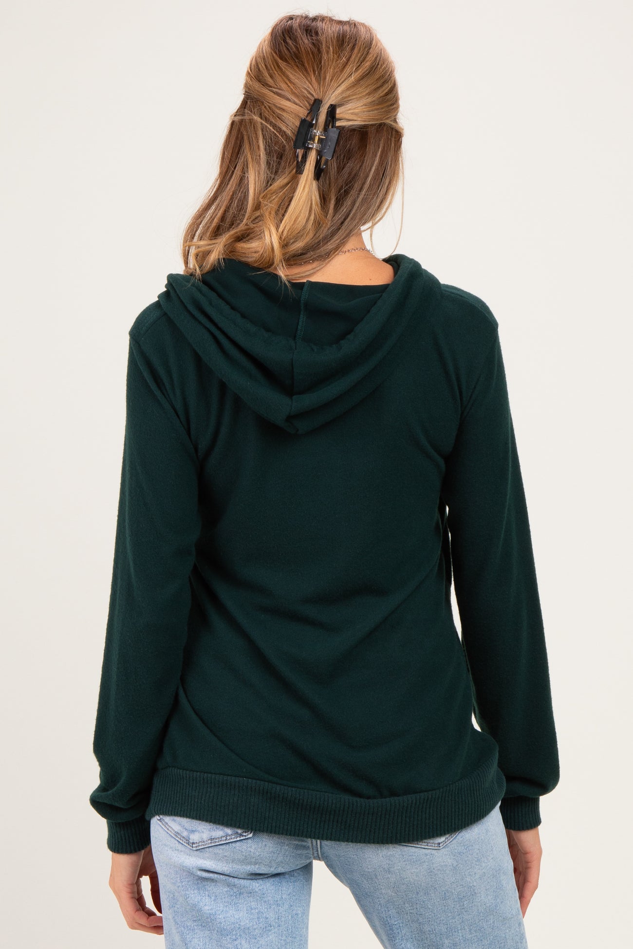 woman wearing a dark green maternity hoodie with a hood, shown from the back