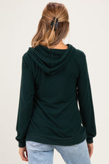 woman wearing a dark green maternity hoodie with a hood, shown from the back