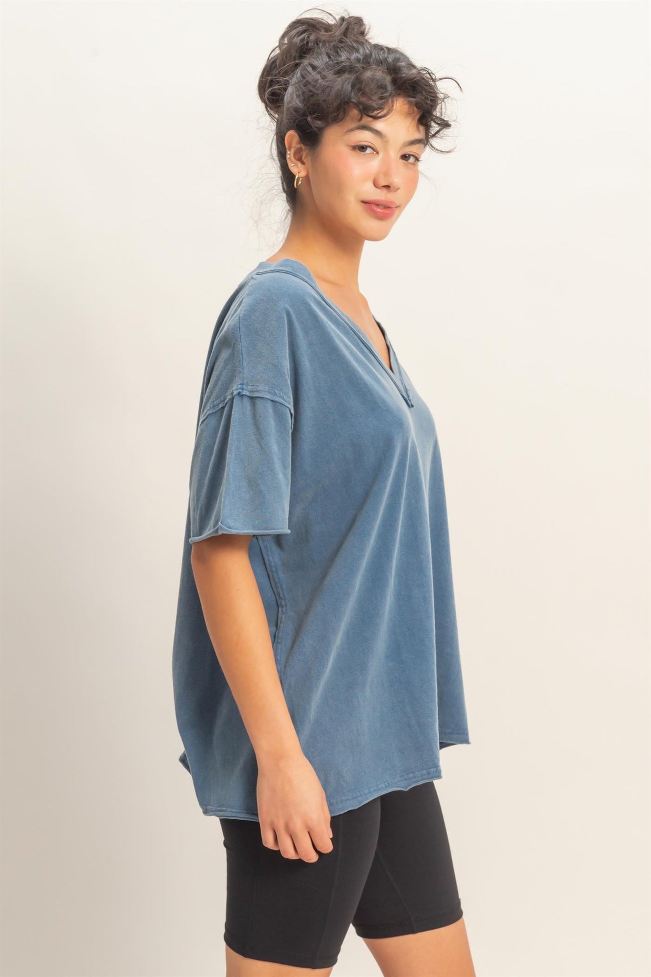 woman wearing a loose-fitting blue v-neck oversized t-shirt with short sleeves and black shorts