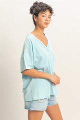 woman wearing a light blue oversized v-neck t-shirt with rolled short sleeves and denim shorts