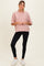 woman wearing a pink striped maternity top and black leggings, standing with a slight smile