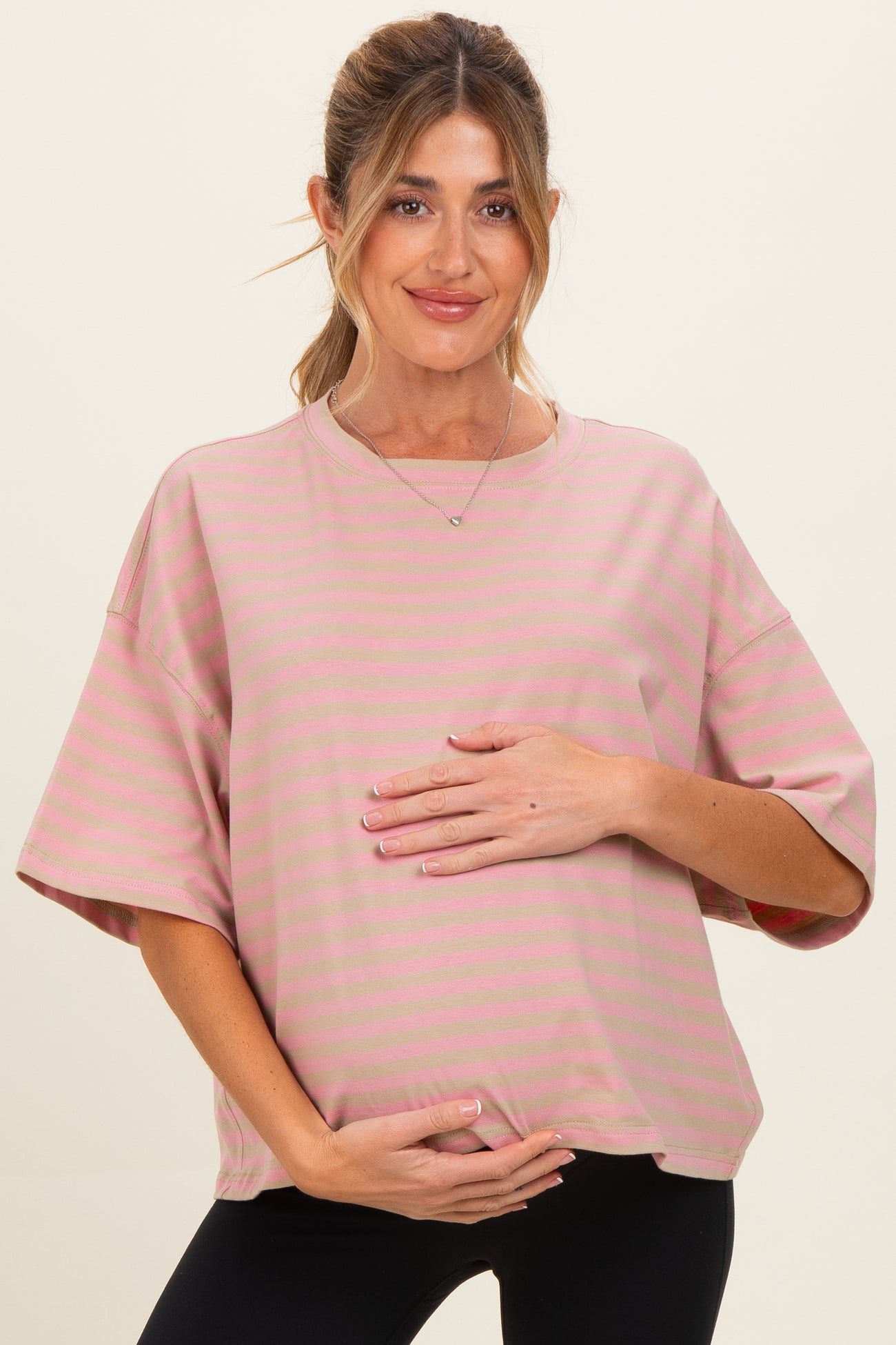 woman wearing a pink striped maternity top and holding her baby bump