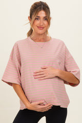 woman wearing a pink striped maternity top and holding her baby bump