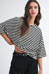 woman wearing a black and white striped oversized t-shirt with wide sleeves and high-waisted black trousers