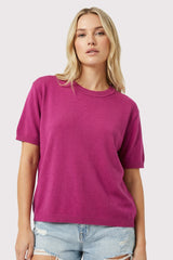 woman wearing a bright pink short sleeve knit sweater with a relaxed fit and casual style